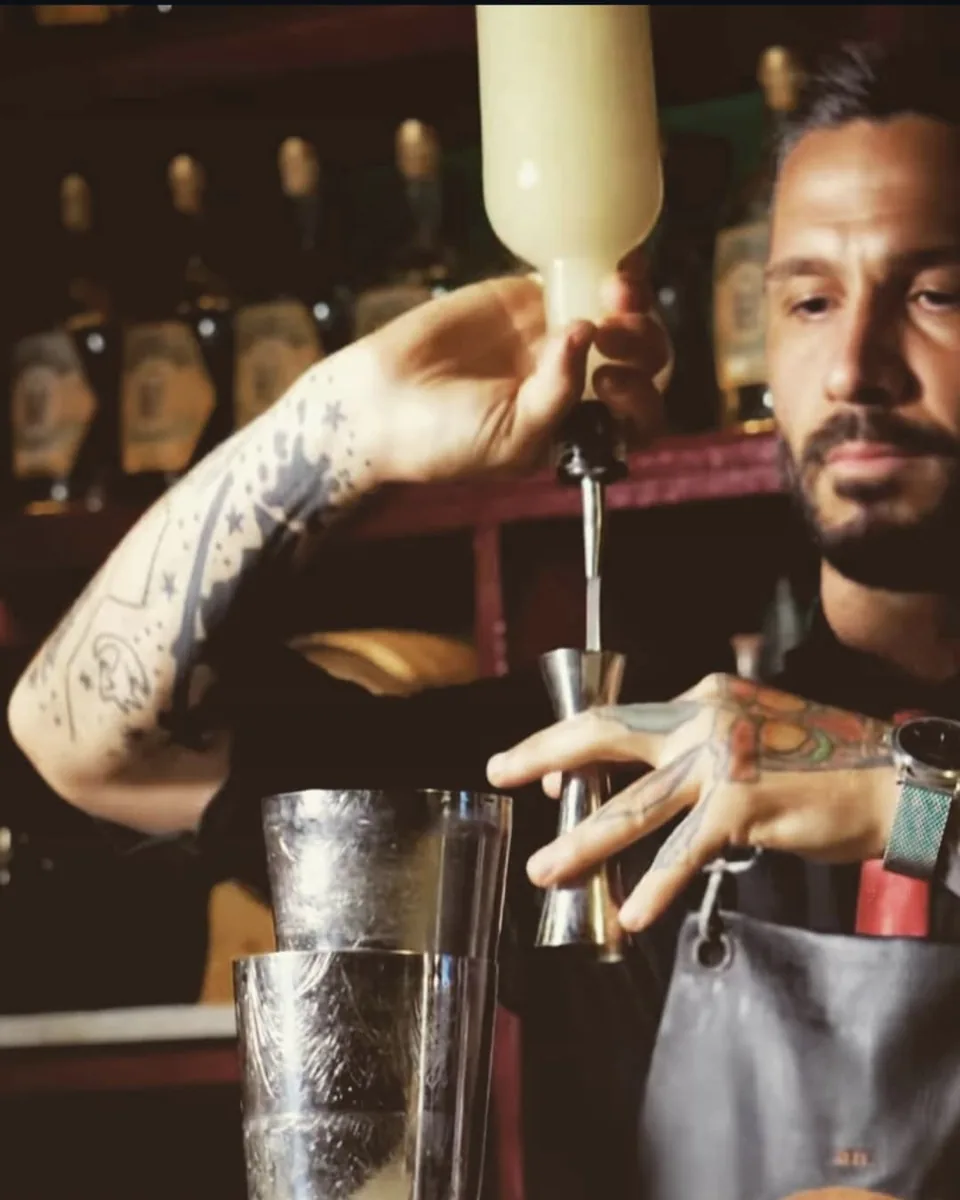 Bartender dello staff che dosa un ingrediente nel jigger, al banco